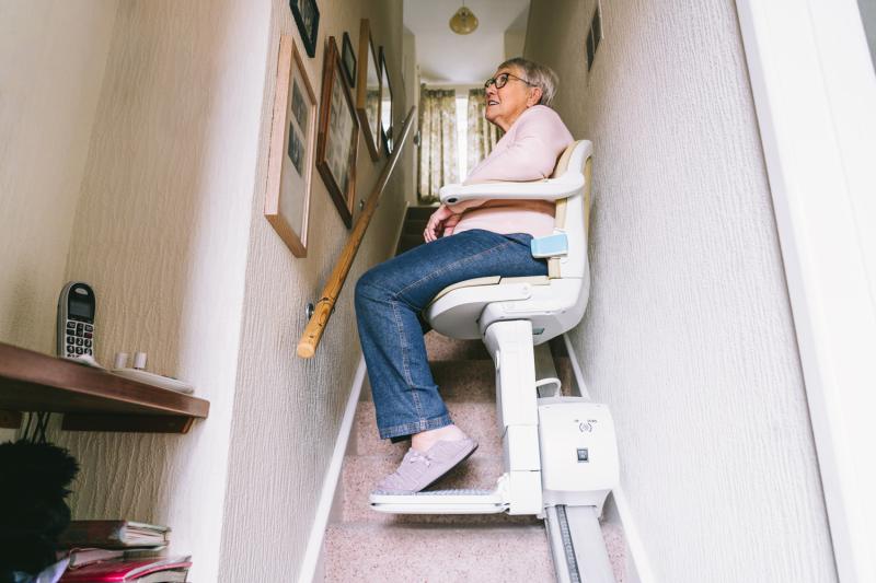 an old lady sitting on the chairlift going up the stairs