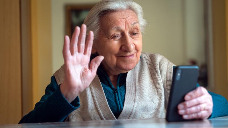 An old lady waiving to her mobile phone on a call